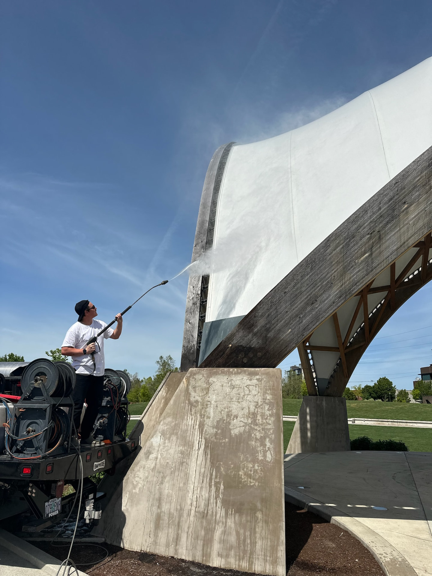 Technician washing a modern architectural structure with a pressure washer