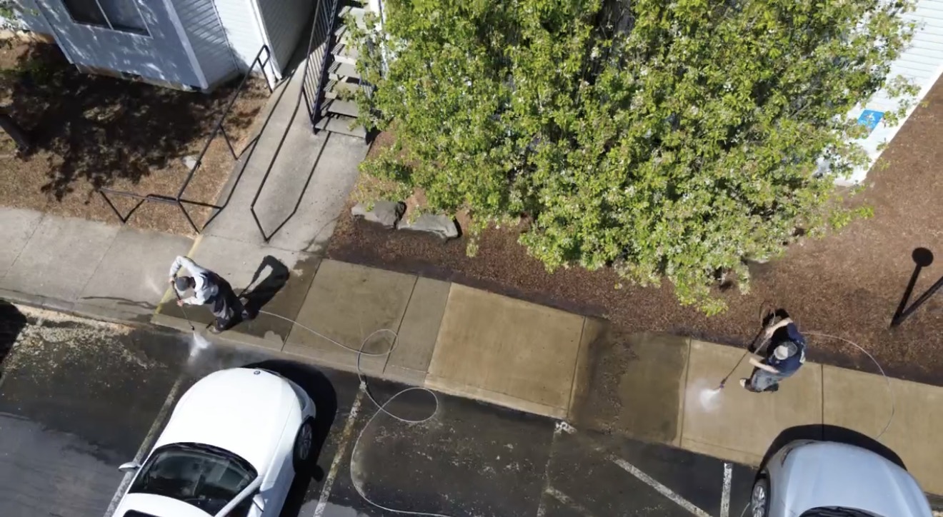 Aerial view of two technicians cleaning commercial sidewalks