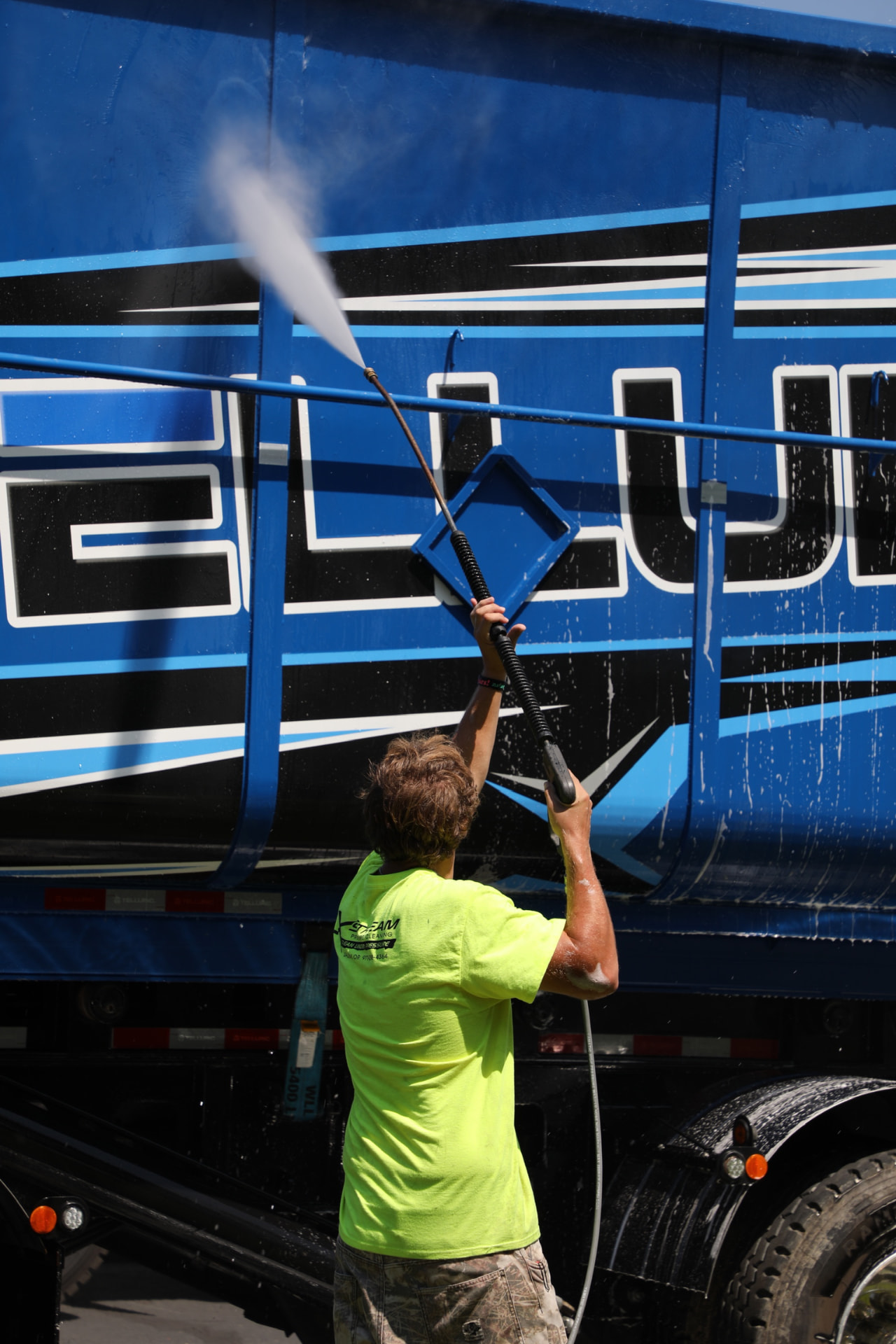 Technician washing a blue semi trailer