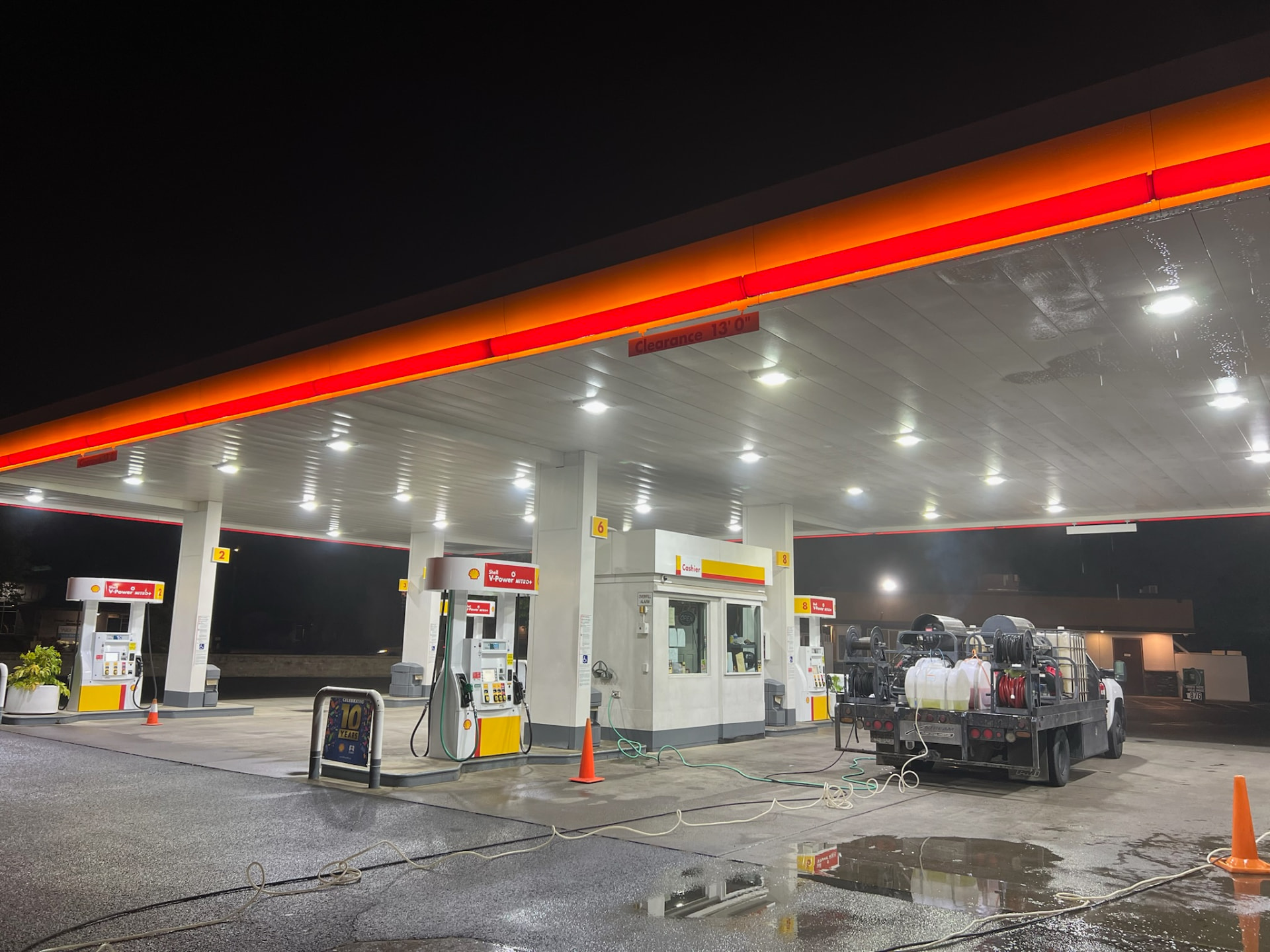 XStream pressure washing rig cleaning a Shell gas station canopy at night