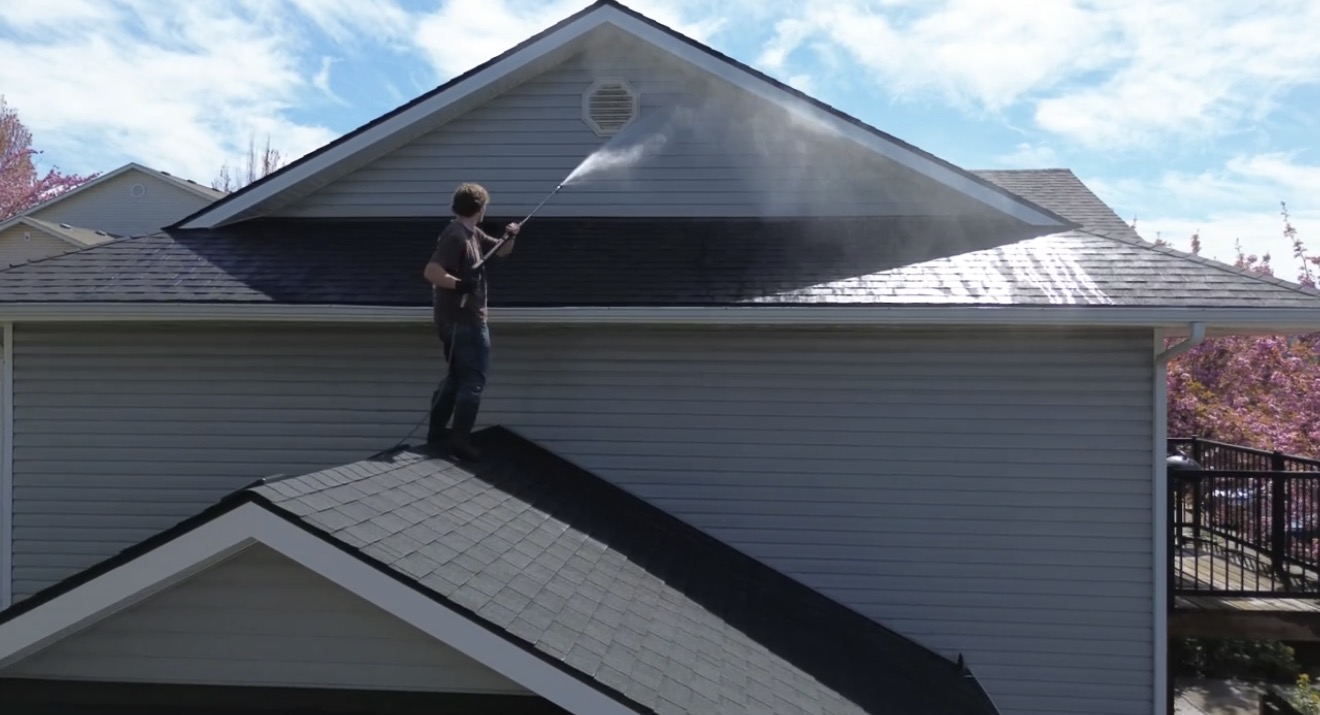 Technician cleaning a residential roof with a pressure washer