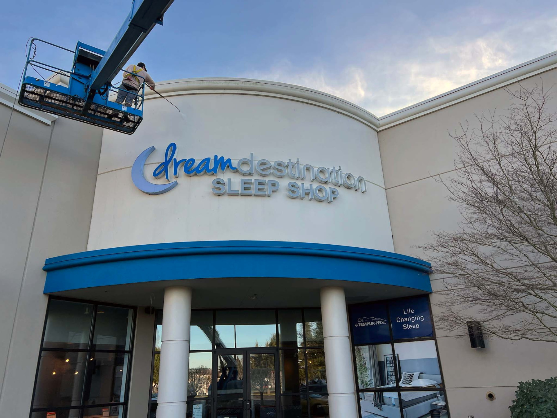 Technician washing a Dream Destination Sleep Shop storefront from a lift