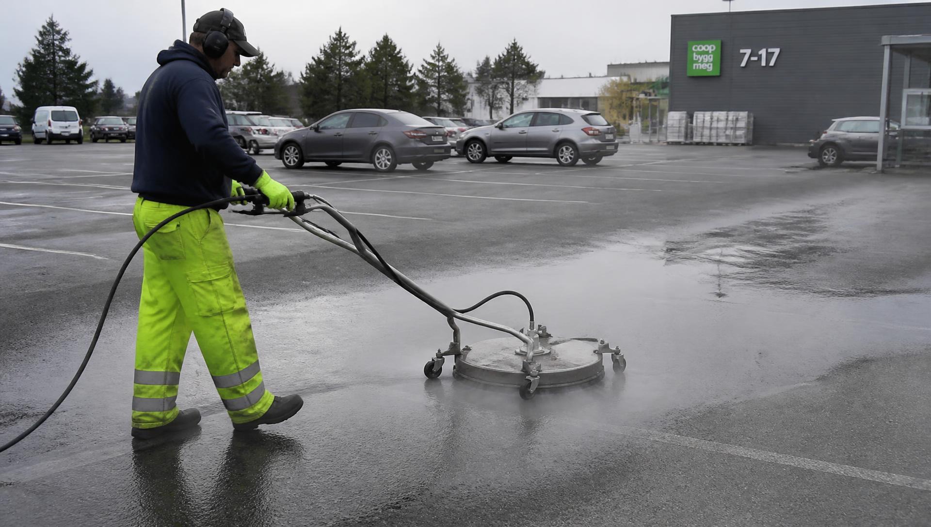 Operator pressure washing a large asphalt parking lot